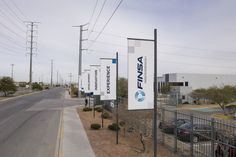 an empty street with cars parked on the side and several signs attached to the fence