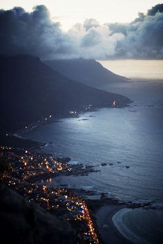 an aerial view of the coastline at night with lights on and clouds in the sky