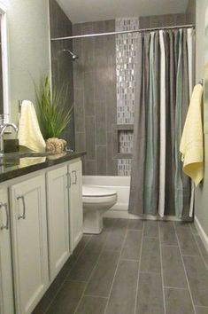 a bathroom with gray tile and white cabinets