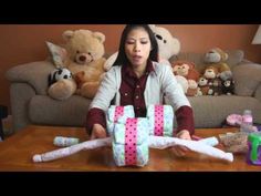 a woman sitting at a table with some wrapping paper and stuffed animals on the couch