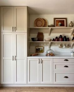 a kitchen with white cupboards and shelves filled with dishes on top of each shelf