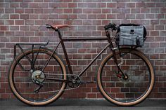 a bike parked next to a brick wall with a bag on the front wheel and seat