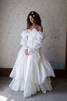 a woman wearing a white dress standing in front of a wall