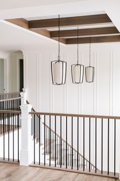 an empty room with white walls and black railings, two hanging lanterns on the wall