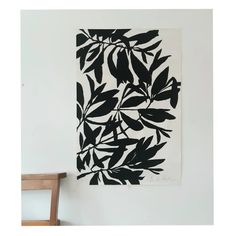 a black and white painting hanging on the wall next to a wooden chair in a room