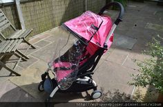 a baby stroller with a pink cover on it's seat and back wheels