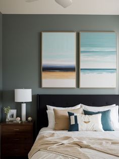 a bedroom with two paintings above the bed