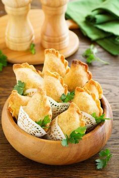 a wooden bowl filled with food on top of a table next to green napkins