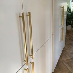 a white refrigerator freezer sitting next to a wall with brass handles on the doors