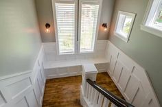 the stairs are lined with white paneling and wood flooring, along with two windows