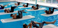 people are doing exercises in the pool on floating mattresses while others watch from the sidelines