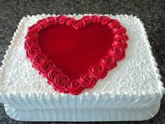 a heart shaped cake sitting on top of a white box with red frosting in the shape of a heart