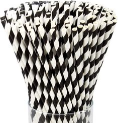 black and white checkered paper straws in a clear glass cup on a white background