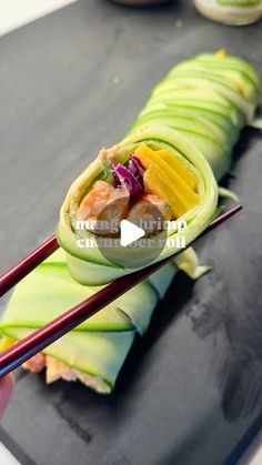 someone is holding chopsticks to eat some food on a black plate with green leaves