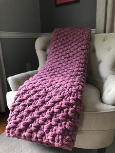 a pink crocheted blanket sitting on top of a white chair