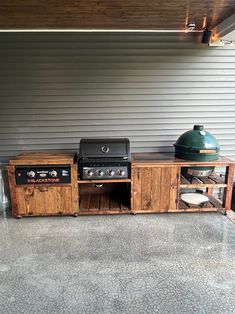 an outdoor bbq and grill area in front of a garage with the door open