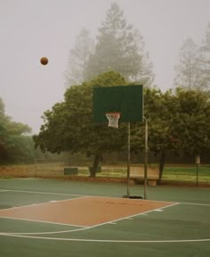 an empty basketball court in the middle of a foggy day with a ball flying through the air