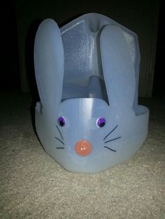 a blue plastic bunny sitting on top of a floor