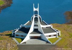 an aerial view of a church in the middle of a body of water with grass growing on top