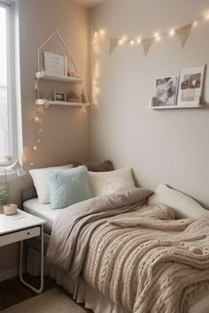 a small bedroom with a bed, desk and lights on the wall above it's headboard