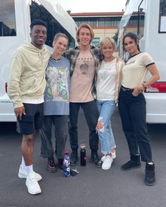 four people standing in front of a white van