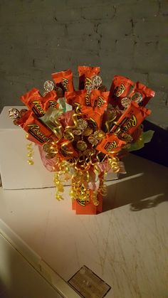 a vase filled with candy on top of a white table next to a brick wall