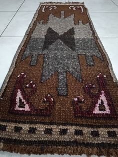 a brown and black rug on the floor with white tiles in the backround