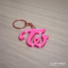 a pink plastic keychain with the letter t and g on it's side