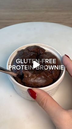 a woman is holding a spoon over a bowl of brownie on a plate with the words glutin - free protein brownie