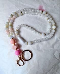 🍎Handmade high quality genuine Morganite and a hire Jade gemstone and crystal lanyard!  This is a one of a kind lanyard made for my back to school sale! Get it while you can! All orders come with a gift from me!  It's made with 8mm morganite and white jade  gemstones in calming pastel and white colors   Made 17.5" long with a Gold lobster clasp and accents.  The closure is a strong breakaway clasp in white. The focal beads are soft silicone beads!  ❤️About morganite and white jade:  Morganite is considered "the stone of divine love." Spiritually, it's thought to bring inner peace, personal growth, and unconditional love for yourself and through relationships with others. Many feel that morganite is associated with the heart chakra. Pastel Morganite has a soft and attractive glow that not White Beaded Lanyard For Personal Use, Lanyard Crystals, Pink Lanyard With Keychain For Personal Use, Personalized Pink Lanyards For Personal Use, Adjustable Personalized Pink Lanyard, Morganite Jewelry, Nurse Badge Holders, Lucky Stone, Beaded Lanyards