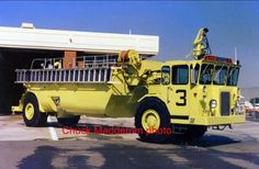 an old yellow fire truck parked in front of a building