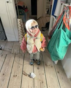 a small child wearing sunglasses standing on a wooden floor