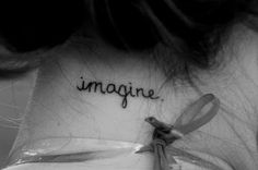 the back of a woman's neck with an inscription on it that reads imagine