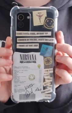 a person holding up a cell phone case with some stickers on it and writing on the back