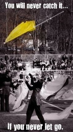 a man holding a yellow kite in front of a group of people on a field