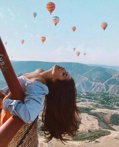 a woman laying on top of a basket with hot air balloons in the sky