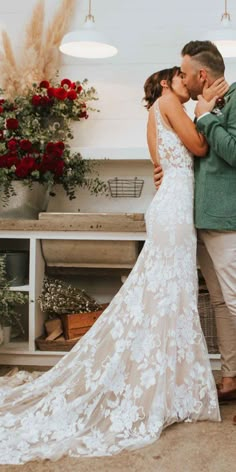 a bride and groom kissing in front of a floral display at their wedding reception venue