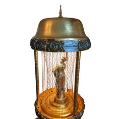 a golden clock with a statue inside of it's caged enclosure on display