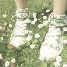 a person standing in the grass with their feet up and white shoes on top of them