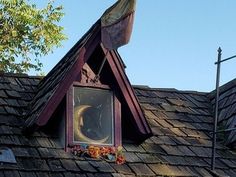 an old house with a flag on top of it and a window in the roof