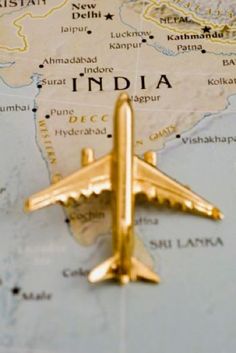 a gold airplane pin on top of a map with the word india written below it