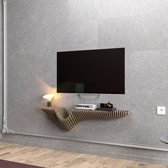 a flat screen tv mounted to the side of a wall next to a table with a lamp on it