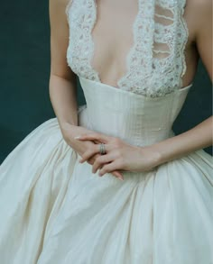 a woman in a white dress holding her hand on her chest and wearing a ring