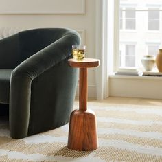 a glass of whiskey sitting on top of a wooden table next to a green chair