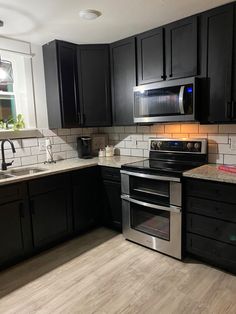 a kitchen with black cabinets and stainless steel appliances