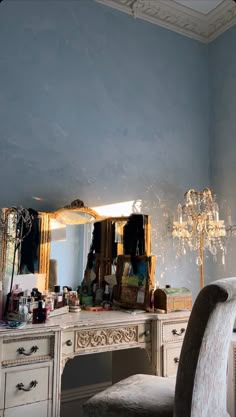 a vanity with a mirror, chair and chandelier in a room that has blue walls