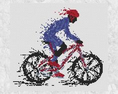 a cross stitch pattern of a person riding a bike with red and blue paint splatters on it