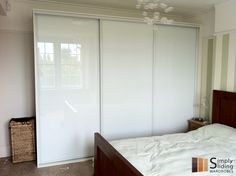 a bedroom with sliding closet doors and a bed in the foreground, an empty basket on the floor next to it