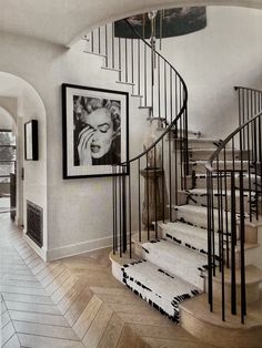 a spiral staircase in a home with pictures on the wall and rugs under it