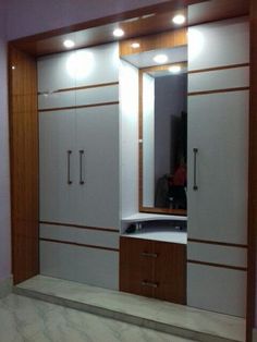 an empty room with white cabinets and lights on the wall, in front of a mirror